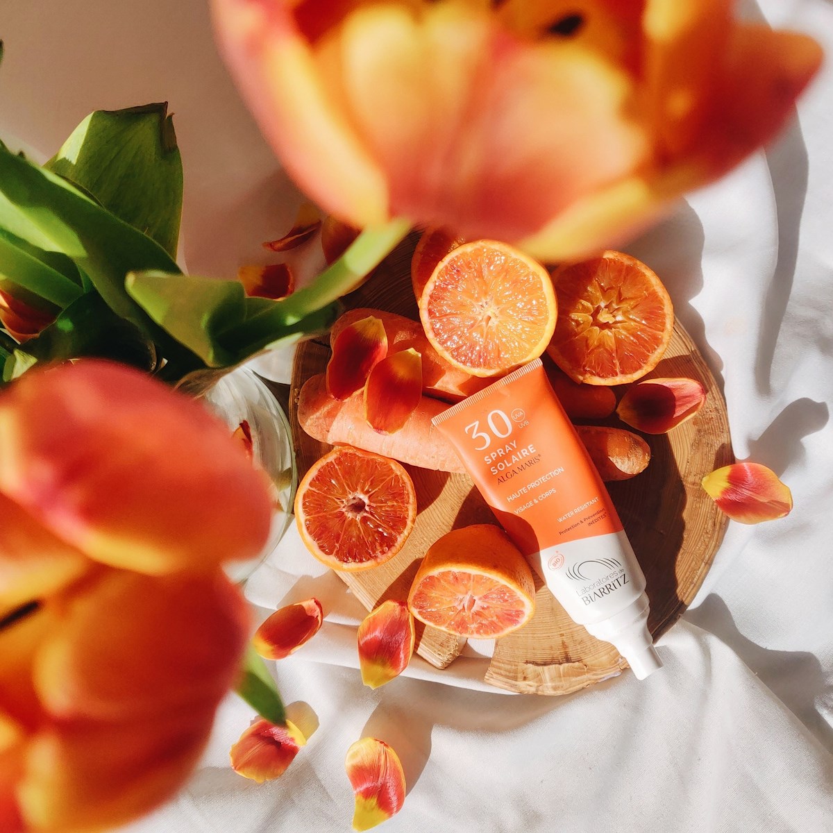 Flatlay with tulips, oranges, carrots and Alga Maris sunscreen
